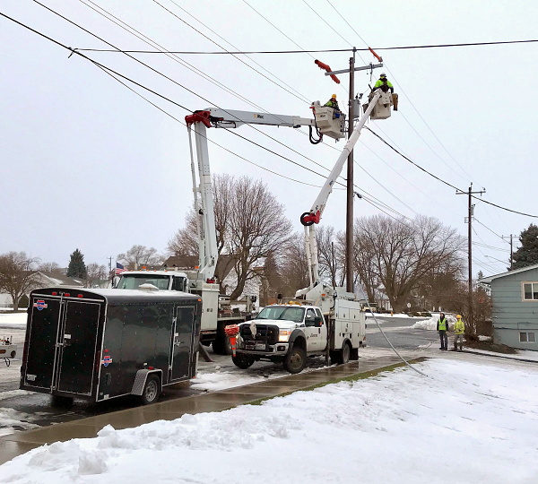 Avista, the local electric utility, connects the new power. Two boom trucks with lineworkers work at the same time. It is cold and snowy.