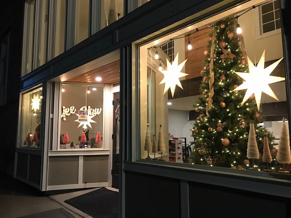The Mercantile is open for business Dec. 22, 2022! View of the exterior at night, highlighting the pretty holiday decorations, including a tall Christmas tree covered with colorful ornaments, and large lighted white stars