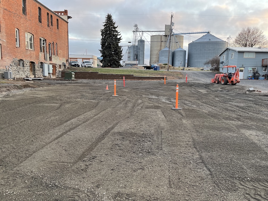 Parking lot behind the hotel almost completed. An orange tractor complements the orange traffic cones on the new gravel